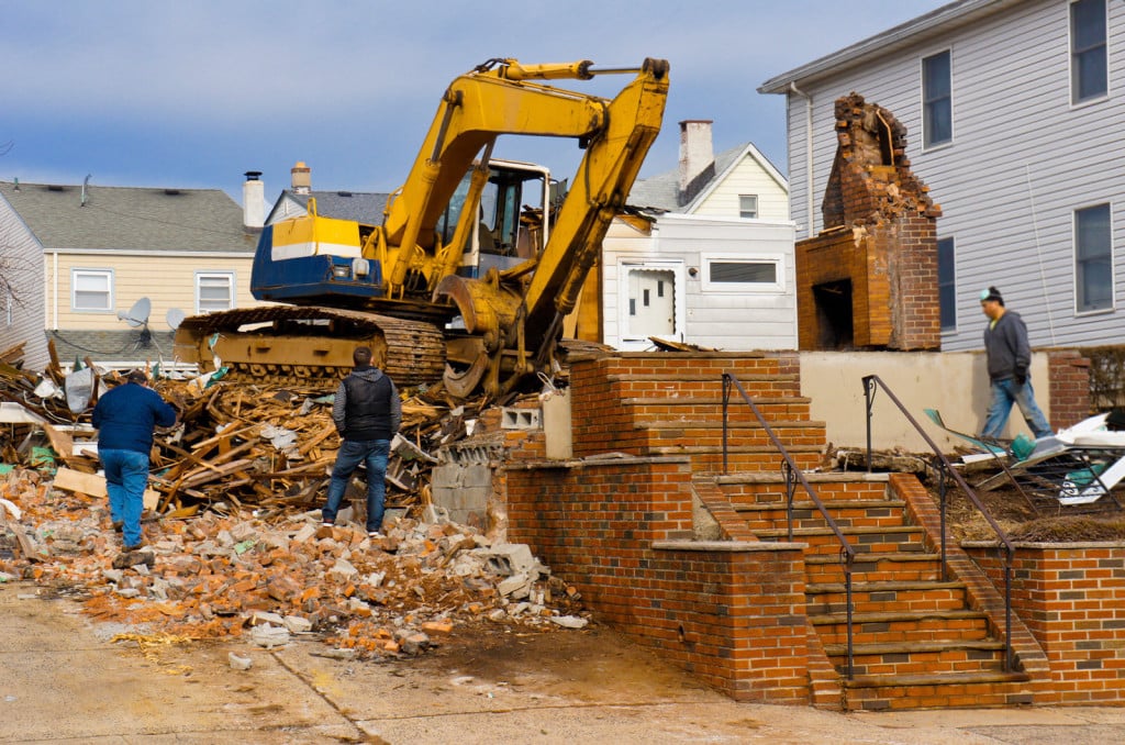 A large backhoe demolishes an old building